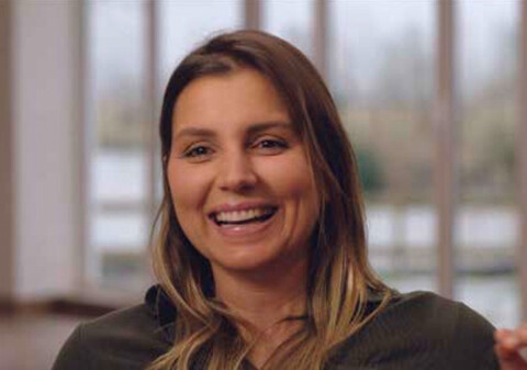 A woman with long light brown hair smiles into the camera